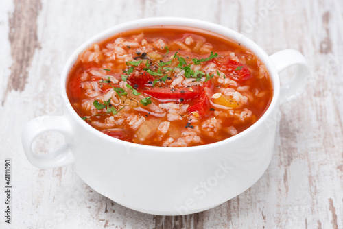 tomato soup with rice and vegetables on white wooden table