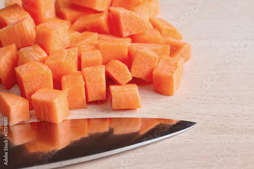Diced raw carrots with knife on a chopping board