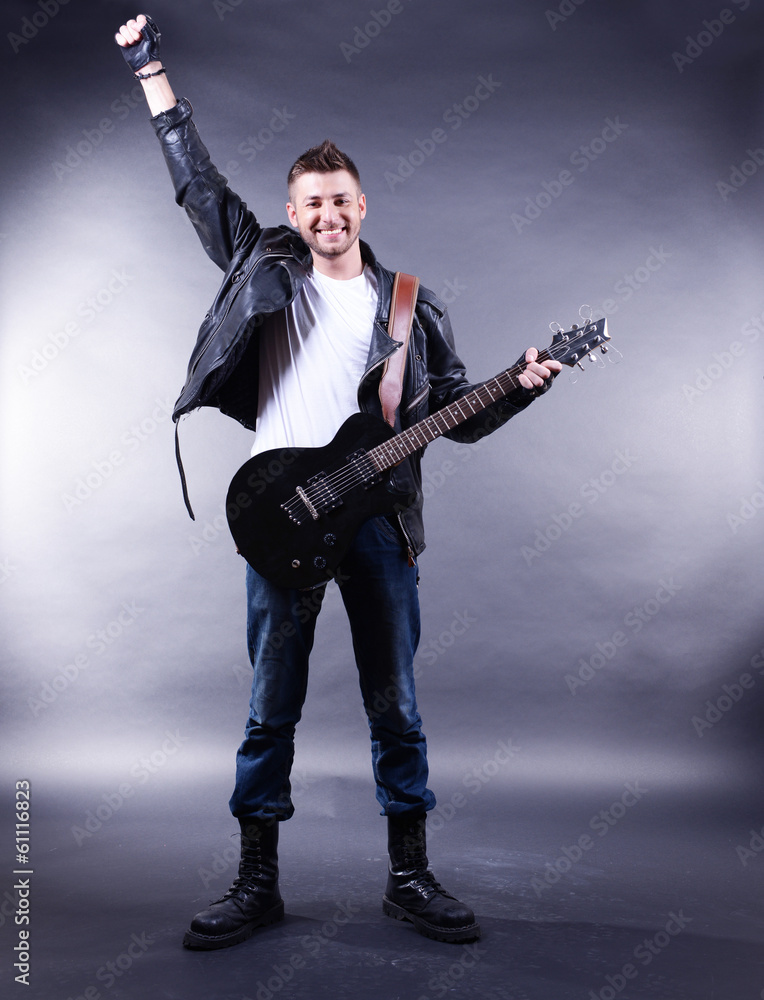 Fototapeta premium Young musician playing guitar on gray background