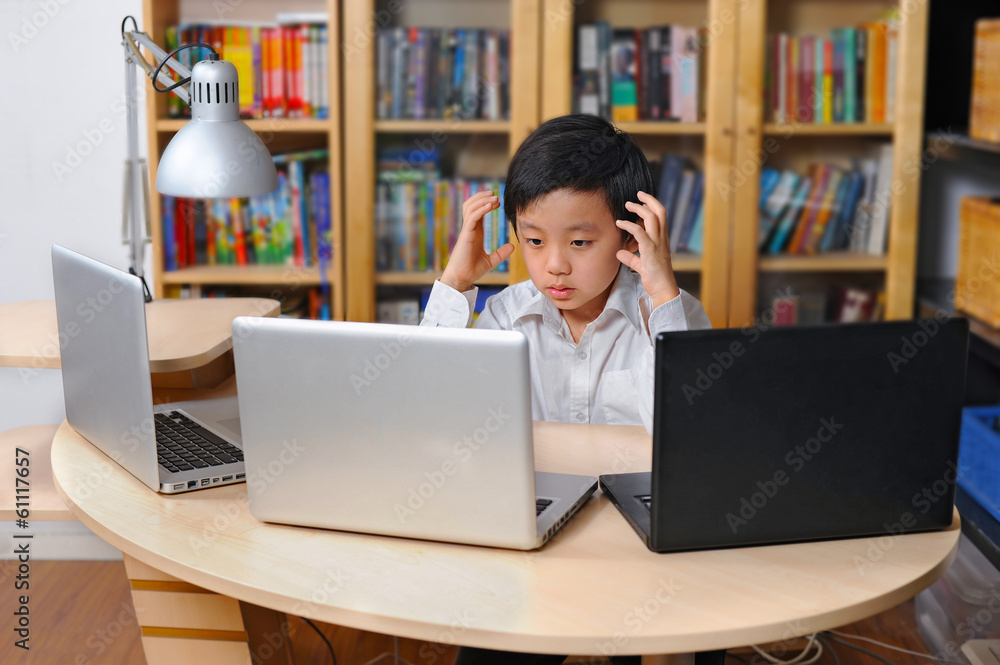 Frustrated Asian boy in front of multiple laptop computers Frustrated Asian boy in front of multiple laptop computers
