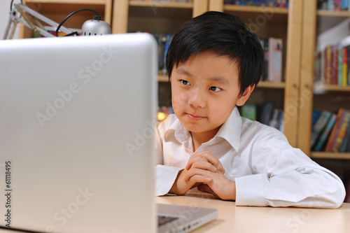 Happy Asian school boy in front of laptop