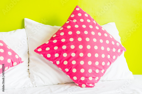 Colorful polka pillow on white bed © siraphol