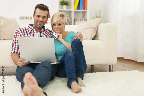 Couple sitting on carpet at home and doing shopping online