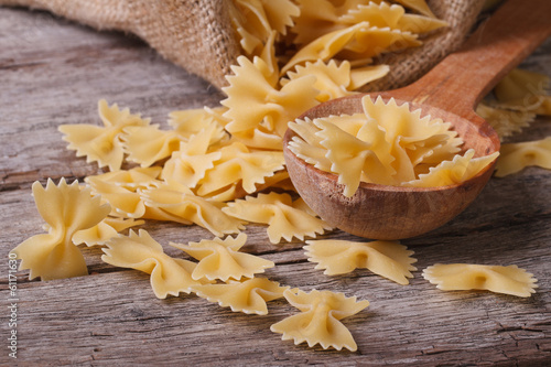 farfalle pasta macro dry on a wooden spoon and an old table photo