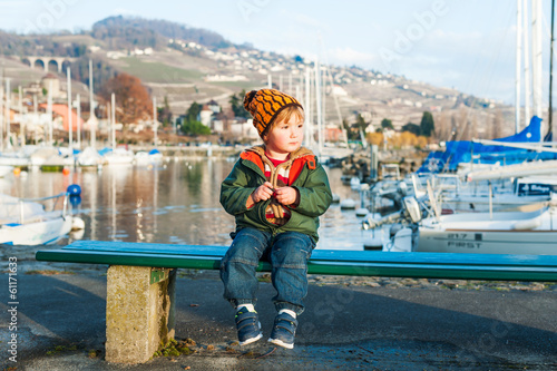 Outdoor portrait of a cute toddler boy sitting on a bench © annanahabed
