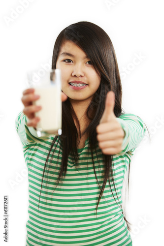 Mädchen hält Milchglas in Hand, andere Hand Daumen-Hoch-Zeichen