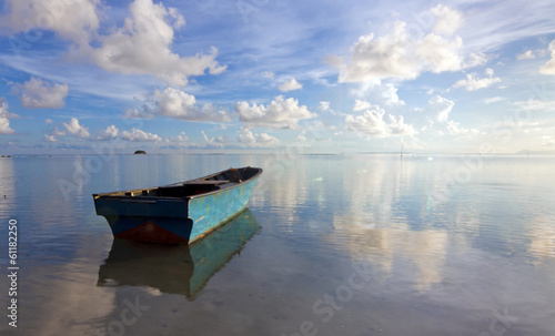 Lonely boat at sea with reflection of blue sky © macbrianmun