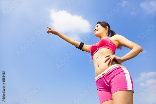 Asian smiling sporty woman watching and pointing far away
