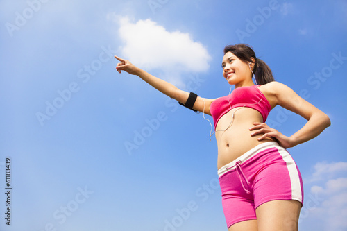smiling sporty woman watching and pointing far away