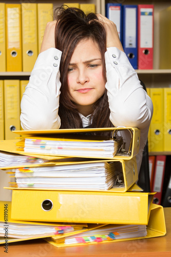 Young secretary distressed with a lot of documents on her desk