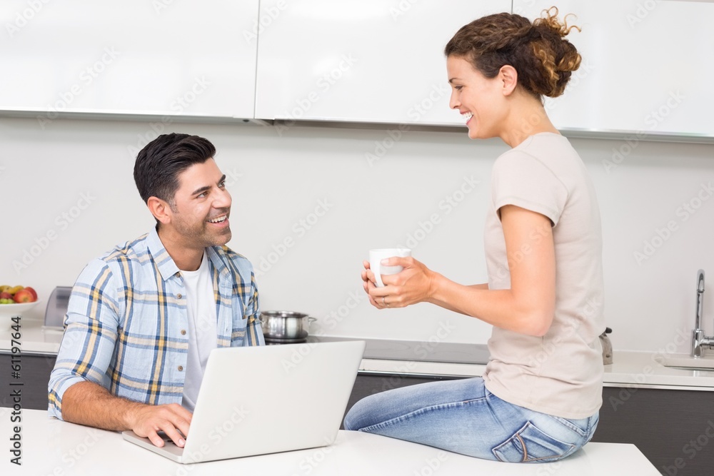 Obraz premium Happy man using laptop while partner sits with a coffee