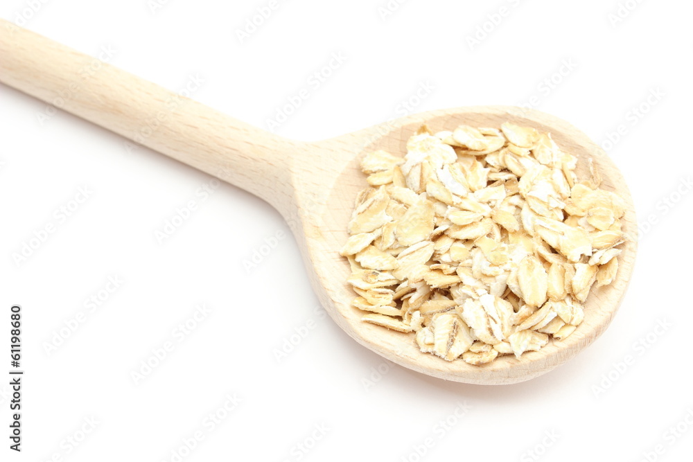 Heap of oatmeal with wooden spoon on white background Heap of oatmeal with wooden spoon on white background