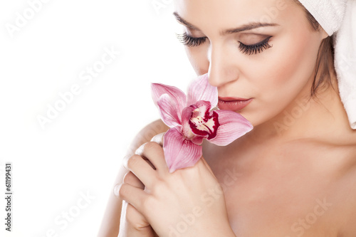 woman with a towel on her head enjoying the scent of orchids