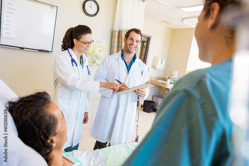 Happy Doctors Discussing Notes With Patient And Nurse In Foregro Happy Doctors Discussing Notes With Patient And Nurse In Foregro