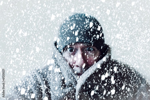 Freezing cold man shivering in a snowstorm with hat and coat and snowflakes blowing all around him. photo