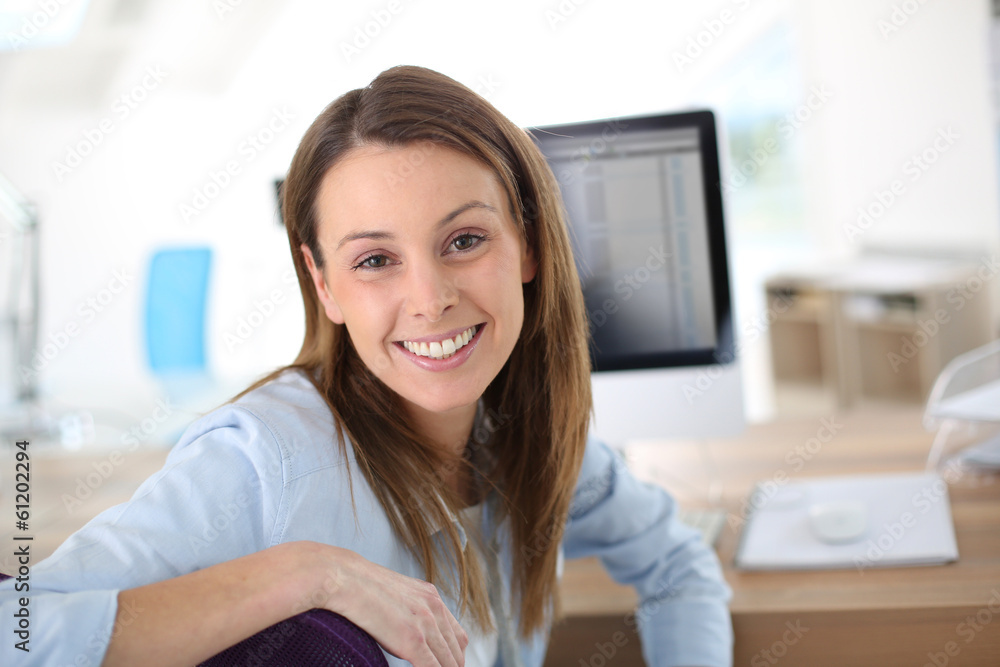Smiling woman in office sitting at desktop Smiling woman in office sitting at desktop