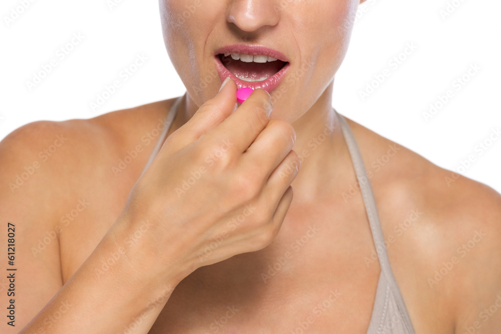 Closeup on young woman eating pill Closeup on young woman eating pill