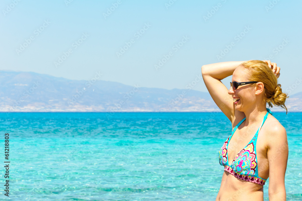 Beautiful young woman in swimsuit, relaxing on a  sunny beach