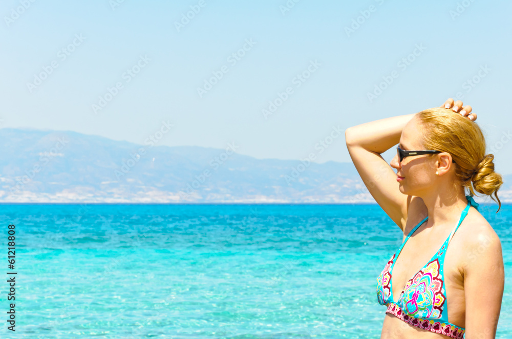Beautiful young woman in swimsuit, relaxing on a sunny beach