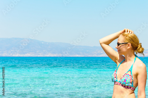 Beautiful young woman in swimsuit, relaxing on a sunny beach