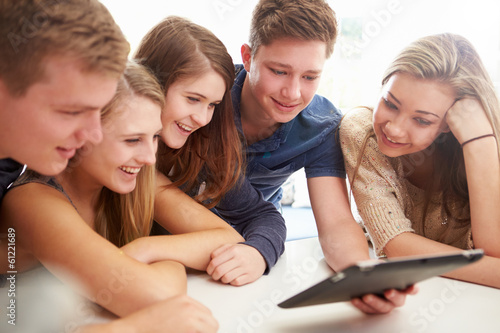 Group Of Teenagers Gathered Around Digital Tablet Together