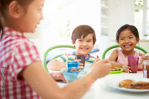 Three Asian Children Having Breakfast Together In Kitchen