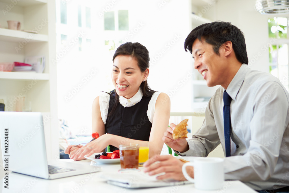 Asian Couple Looking at Laptop Over Breakfast Asian Couple Looking at Laptop Over Breakfast