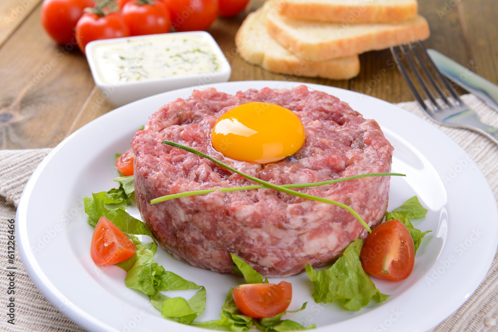 Delicious steak tartare with yolk on plate on table close-up Delicious steak tartare with yolk on plate on table close-up