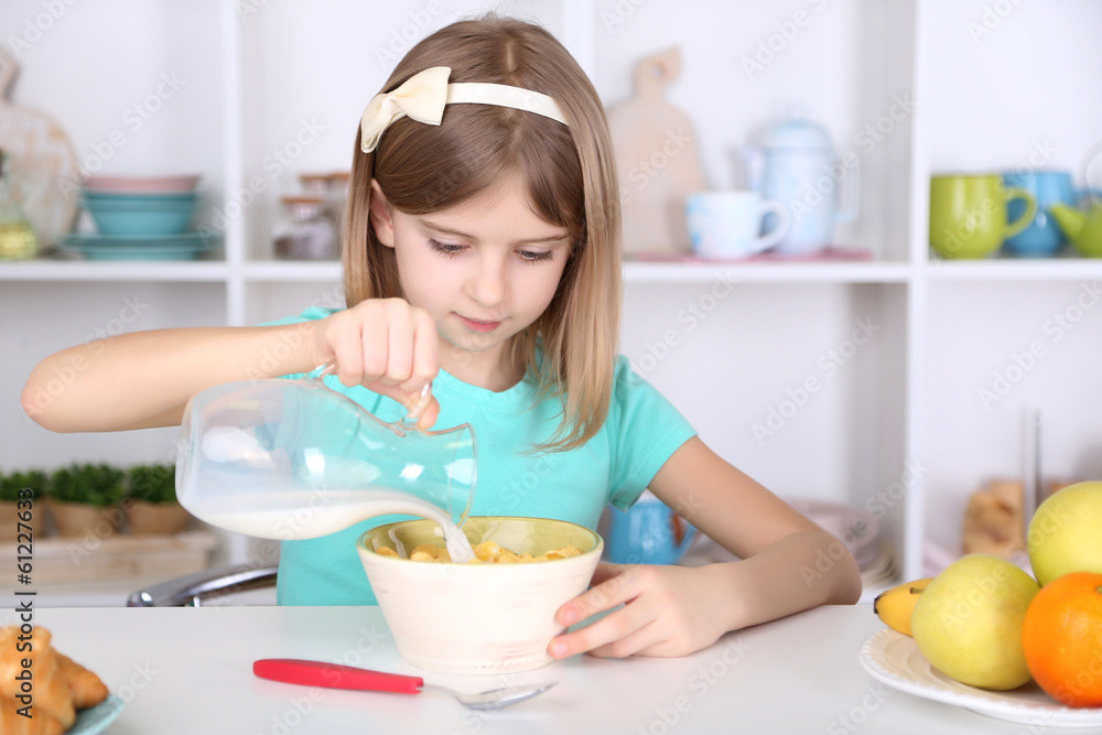 Beautiful little girl eating breakfast in kitchen at home Beautiful little girl eating breakfast in kitchen at home