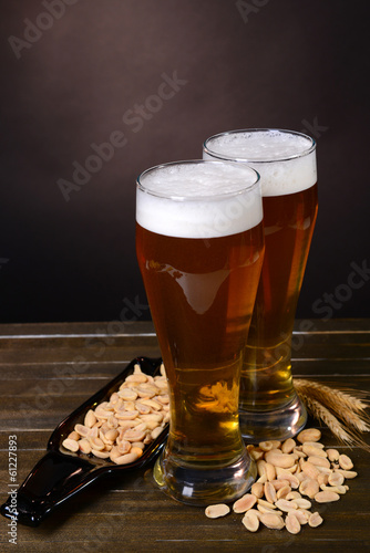 Glasses of beer with snack on table on dark background