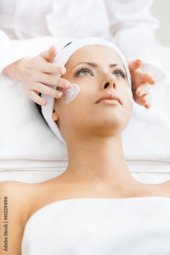 Hands of therapist apply cream to face of woman Hands of therapist apply cream to face of woman