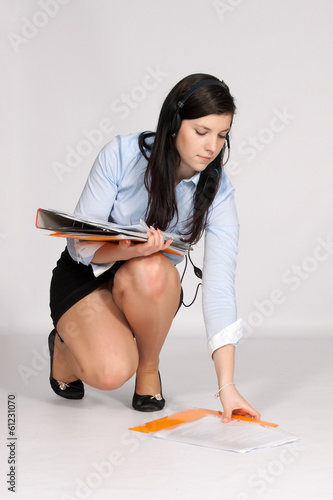 Young woman in mini skirt and blouse, squatting rises from the g