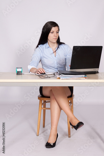 Female poses behind a desk in the office