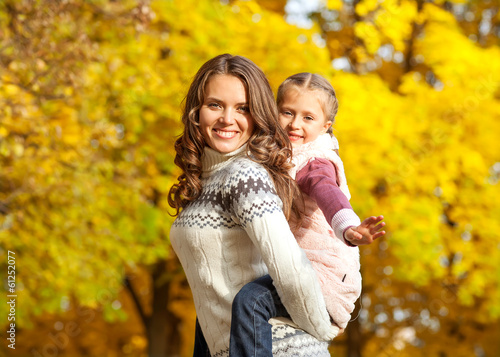 Young mother and her toddler girl have fun in autumn