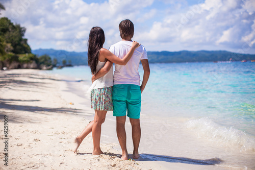 Young couple walking on sandy beach near the sea