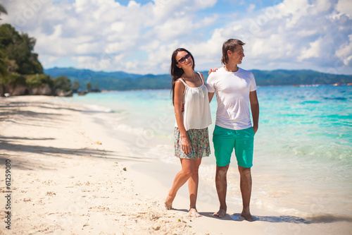 Young couple walking on sandy beach near the sea