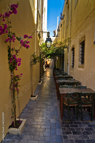 Restaurant in shade at street of old city and harbor, Crete