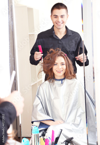 Young man hairdresser do hairstyle girl in beauty salon