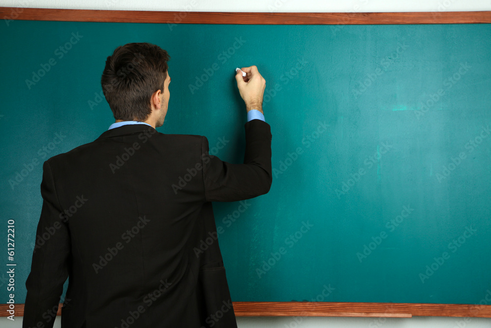Young teacher near chalkboard in school classroom Young teacher near chalkboard in school classroom