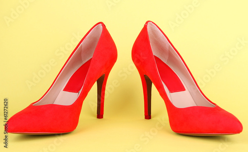 Beautiful red female shoes, on yellow background