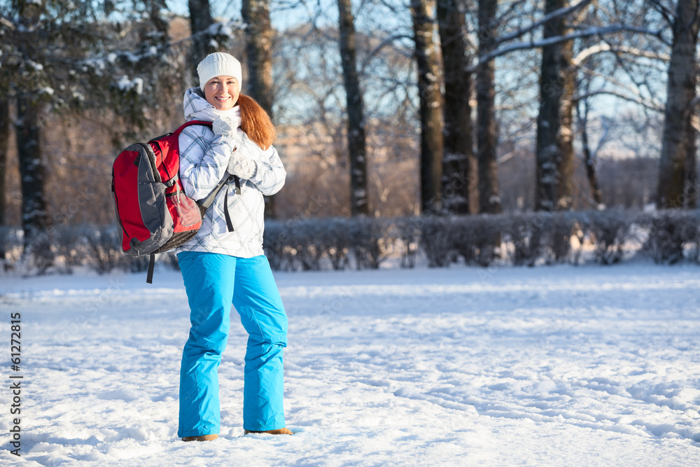 Young woman walking with backpack in winter park, copyspace