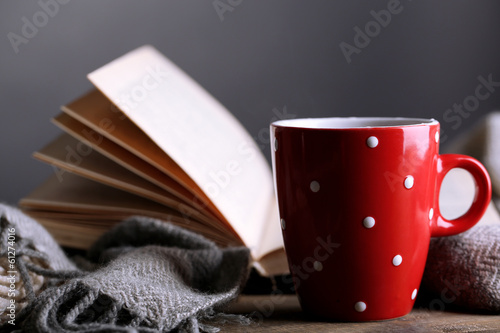 Cup of hot tea with book and plaid on table on gray background