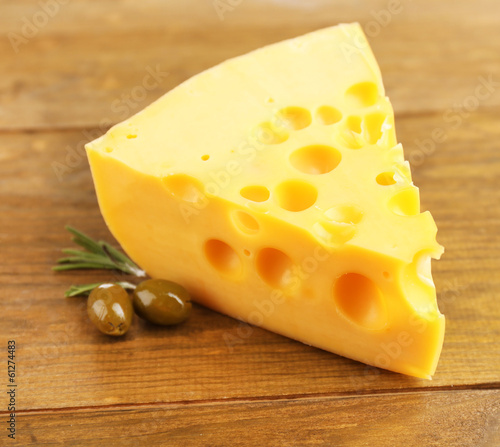 Piece of cheese with green olives, on wooden background