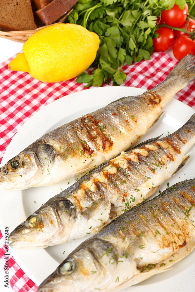 Delicious grilled fish on plate on table close-up Delicious grilled fish on plate on table close-up