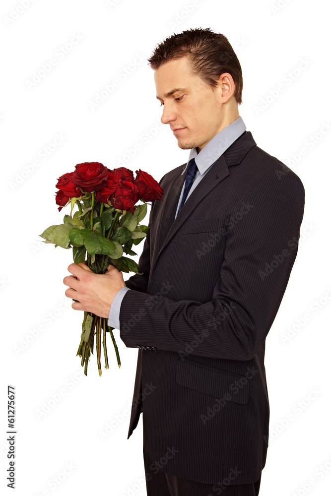 Young man in a suit looking at a bouquet of roses Young man in a suit looking at a bouquet of roses