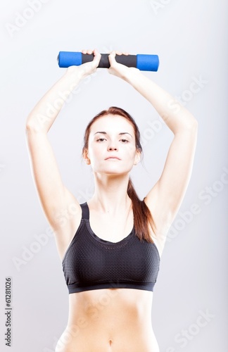 Young fit woman in sport bra during exercise with dumbbells