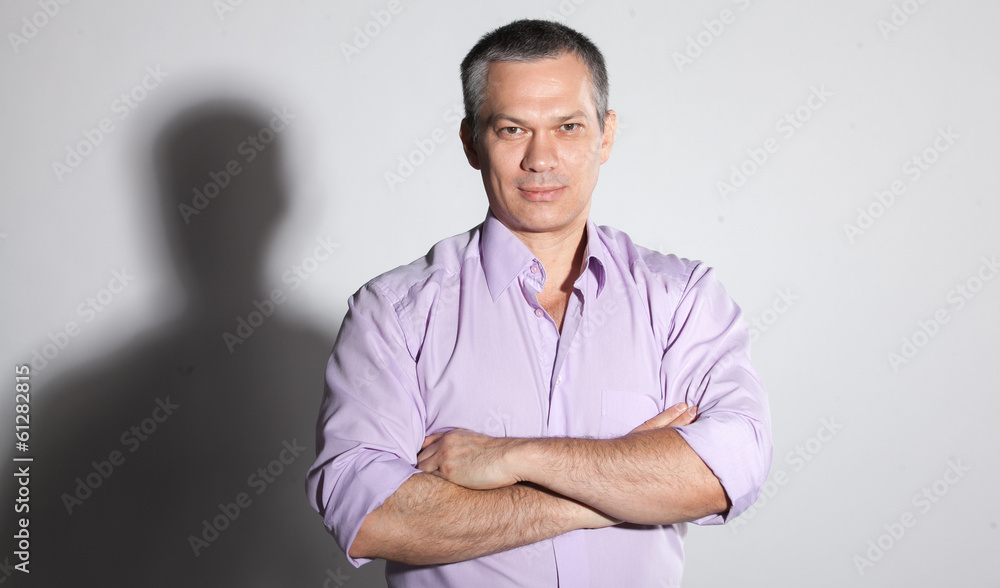 Closeup portrait of adult man in pink shirt holding arms crossed Closeup portrait of adult man in pink shirt holding arms crossed