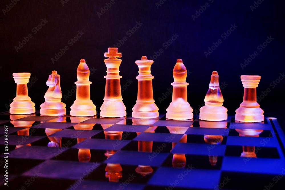 Glass chess on a chess board lit by blue and orange light