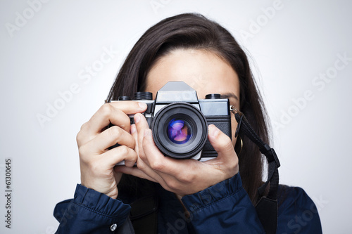 Woman photographer with camera against gray background