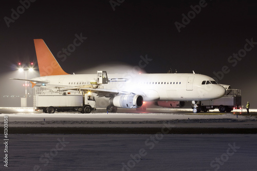 Fototapeta Naklejka Na Ścianę i Meble -  White plane with red tail during de-icing in winter